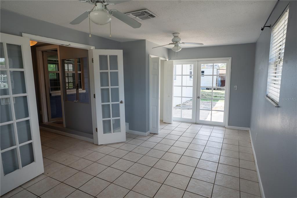 A room with light blue walls, tile flooring, two ceiling fans, and white French doors — 711 MASON STREET, BRANDON, FL