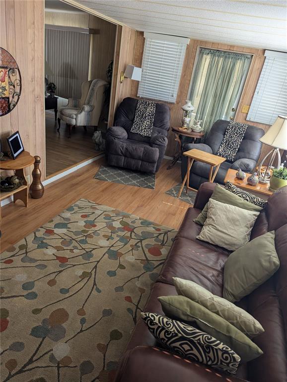 A living room features wood-paneled walls, a patterned area rug, and several leather recliners — 34214 CANAL DRIVE N, PINELLAS PARK, FL