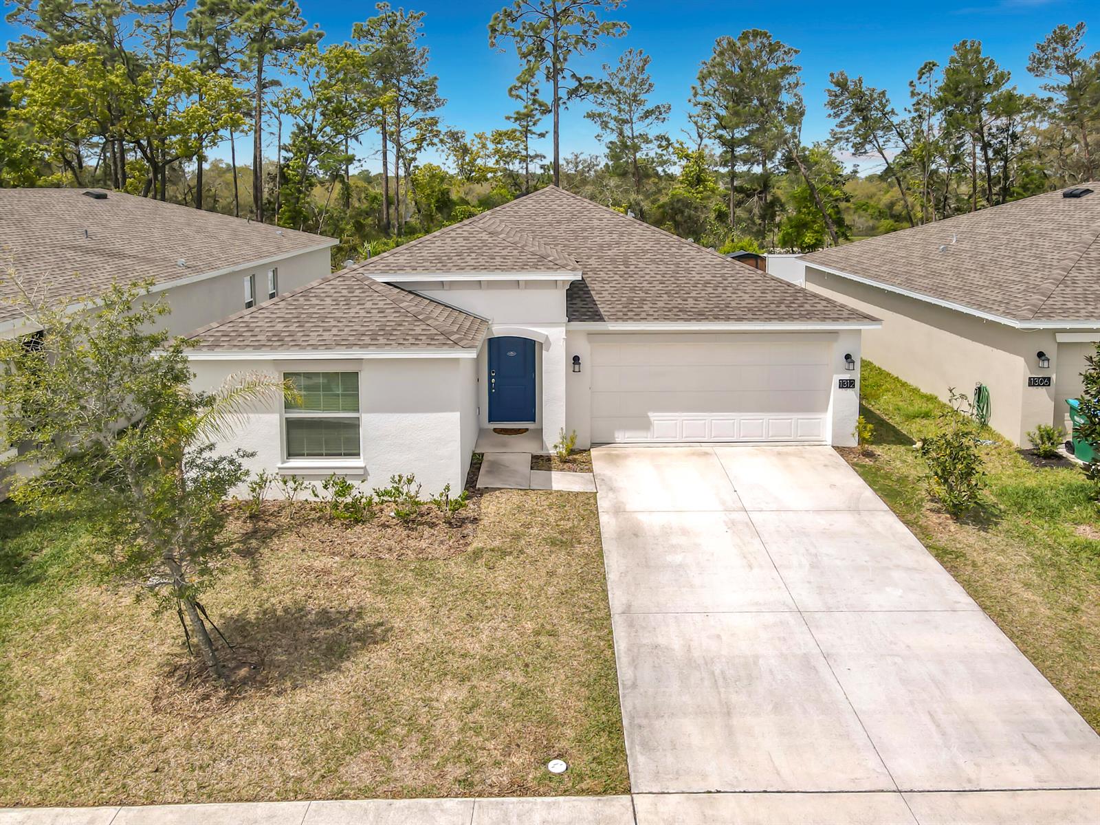 A single-story white house with a blue front door and a concrete driveway — 1312 Peach Creek Drive, FL 32764, FL