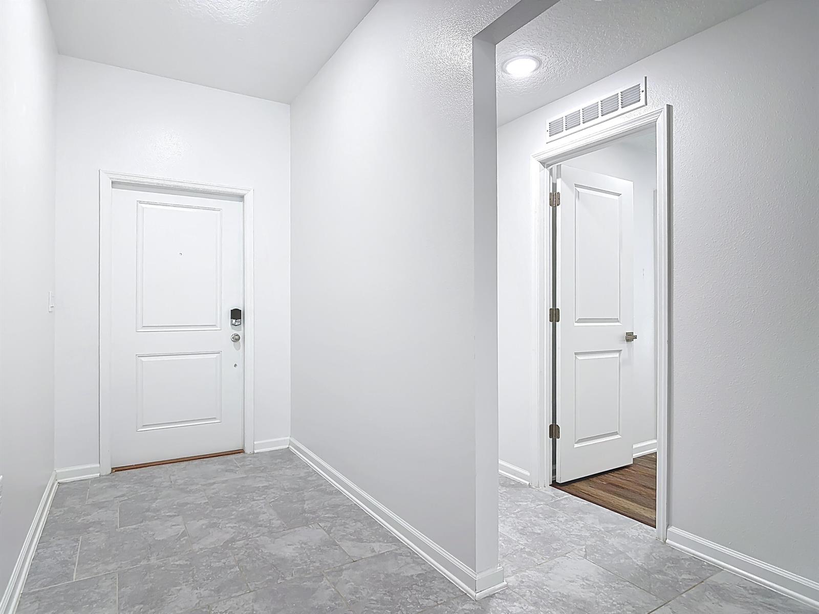 An entryway with gray tile flooring features a white front door and an interior doorway — 1312 Peach Creek Drive, FL 32764, FL