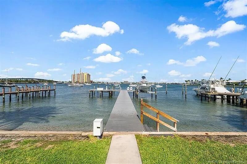 A wooden dock extends into a bay with several boats moored nearby — 2941 Lake Drive, Singer Island FL 33404, SINGER ISLAND, FL
