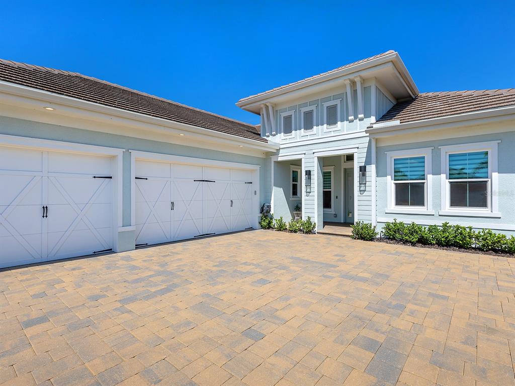 A light blue house with a three-car garage and a paved driveway under a clear sky — 16903 VERONA PLACE, LAKEWOOD RANCH, FL