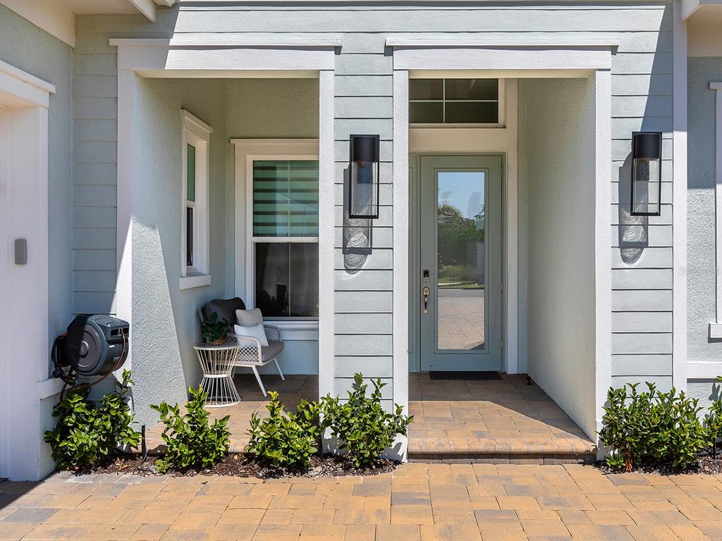 A light blue house exterior features a covered entryway with a glass-paneled door and patio — 16903 VERONA PLACE, LAKEWOOD RANCH, FL