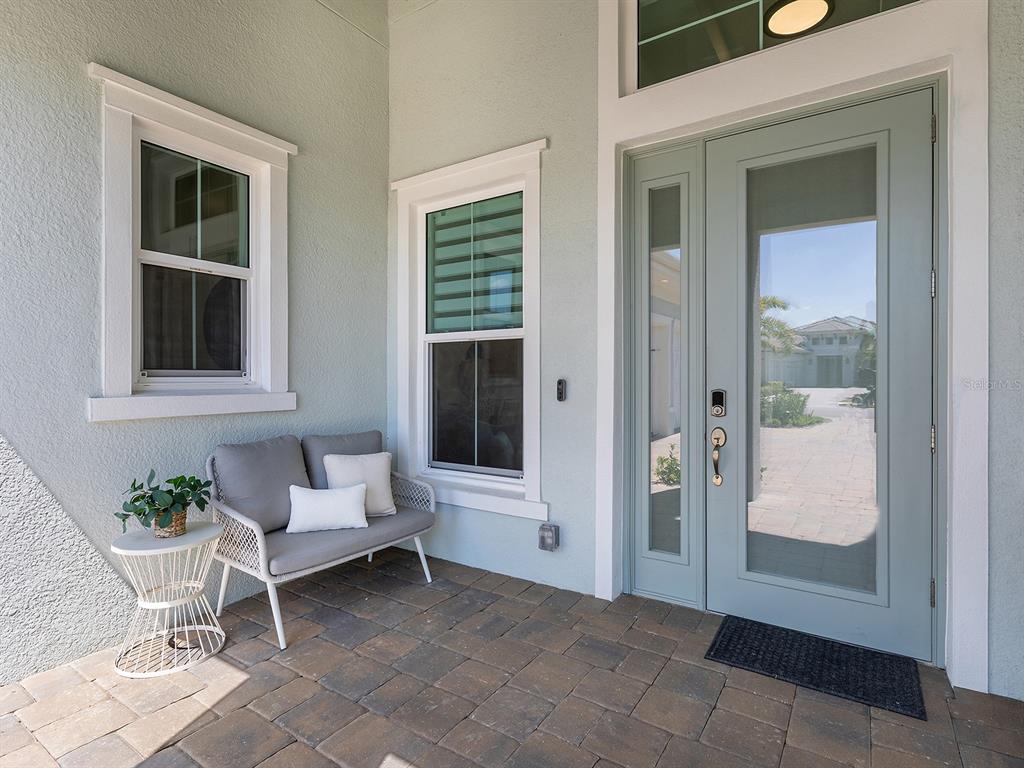A light blue front door and a small gray bench sit on a paved porch — 16903 VERONA PLACE, LAKEWOOD RANCH, FL