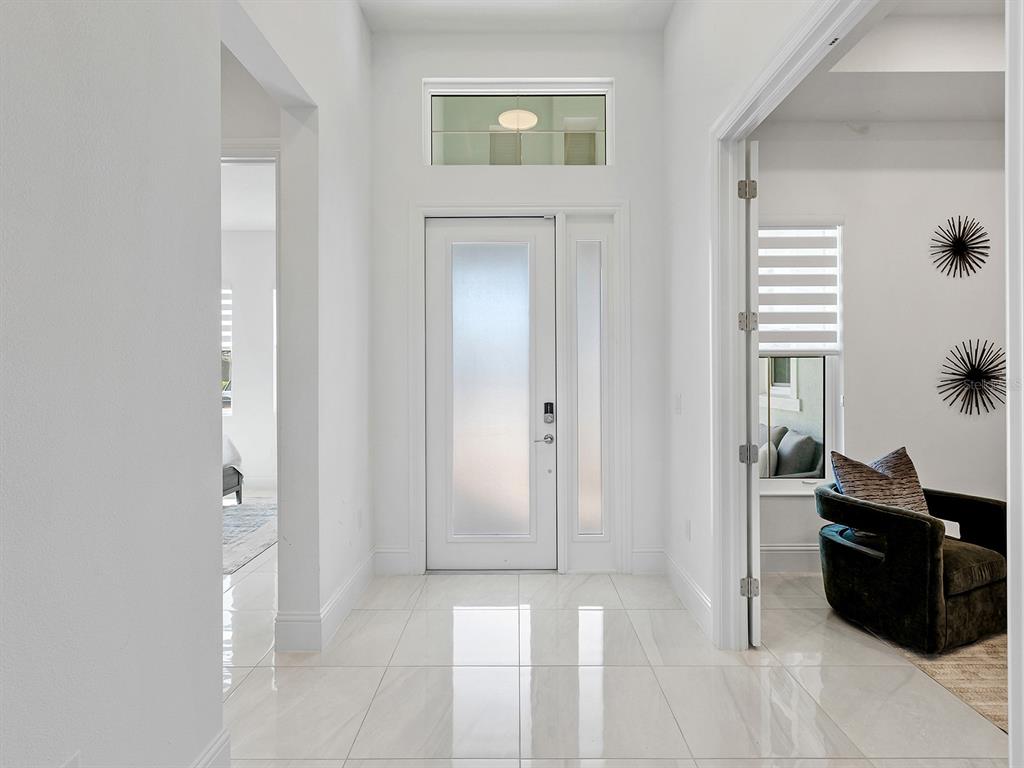 A bright entryway features white walls, polished tile floors, and a frosted glass front door — 16903 VERONA PLACE, LAKEWOOD RANCH, FL