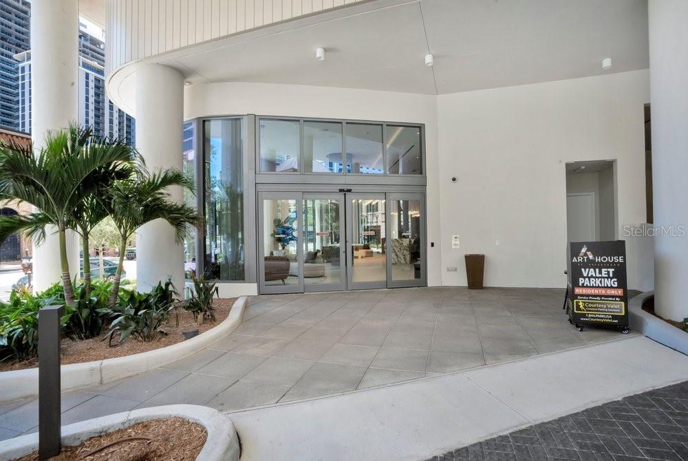 The exterior entrance of a modern building features a valet parking sign and glass doors — 275 1ST AVENUE S UNIT 3808, ST PETERSBURG, FL