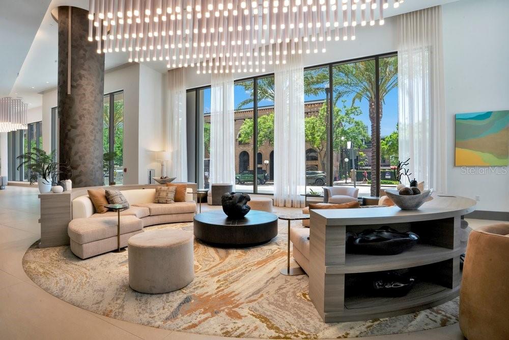 A modern lobby features a large circular rug, curved seating, and a prominent light fixture — 275 1ST AVENUE S UNIT 3808, ST PETERSBURG, FL