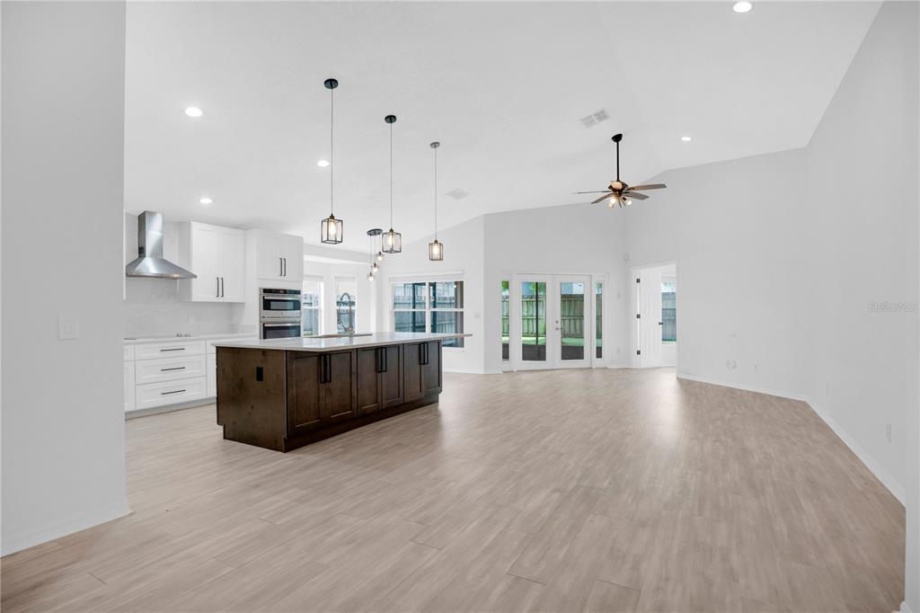 A modern kitchen with a dark wood island and white cabinets opens to a living area — 14170 SUNRIVER AVENUE, ORLANDO, FL