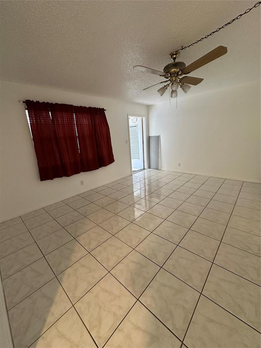 An empty room features white walls, light-colored tile flooring, a ceiling fan, and red curtains — 348 S Federal Highway # 2, Dania Beach FL 33004, DANIA BEACH, FL