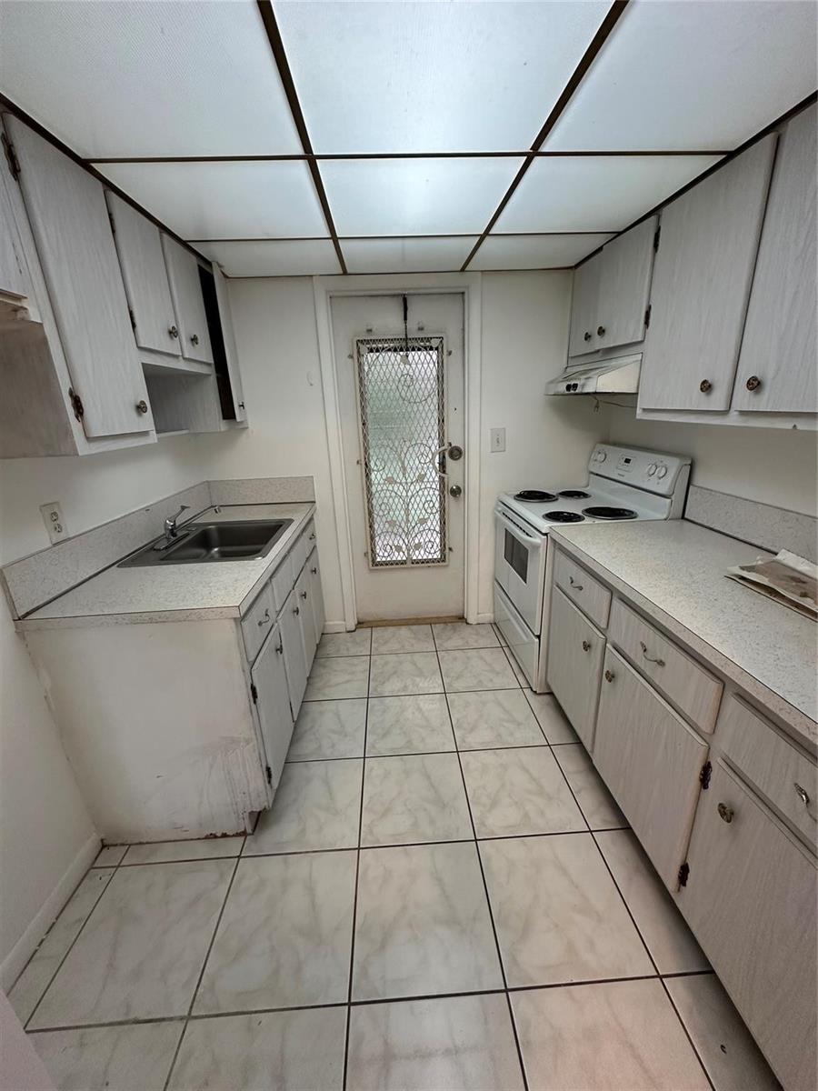 A galley kitchen features white cabinets, laminate countertops, a white stove, and tiled flooring — 348 S Federal Highway # 2, Dania Beach FL 33004, DANIA BEACH, FL