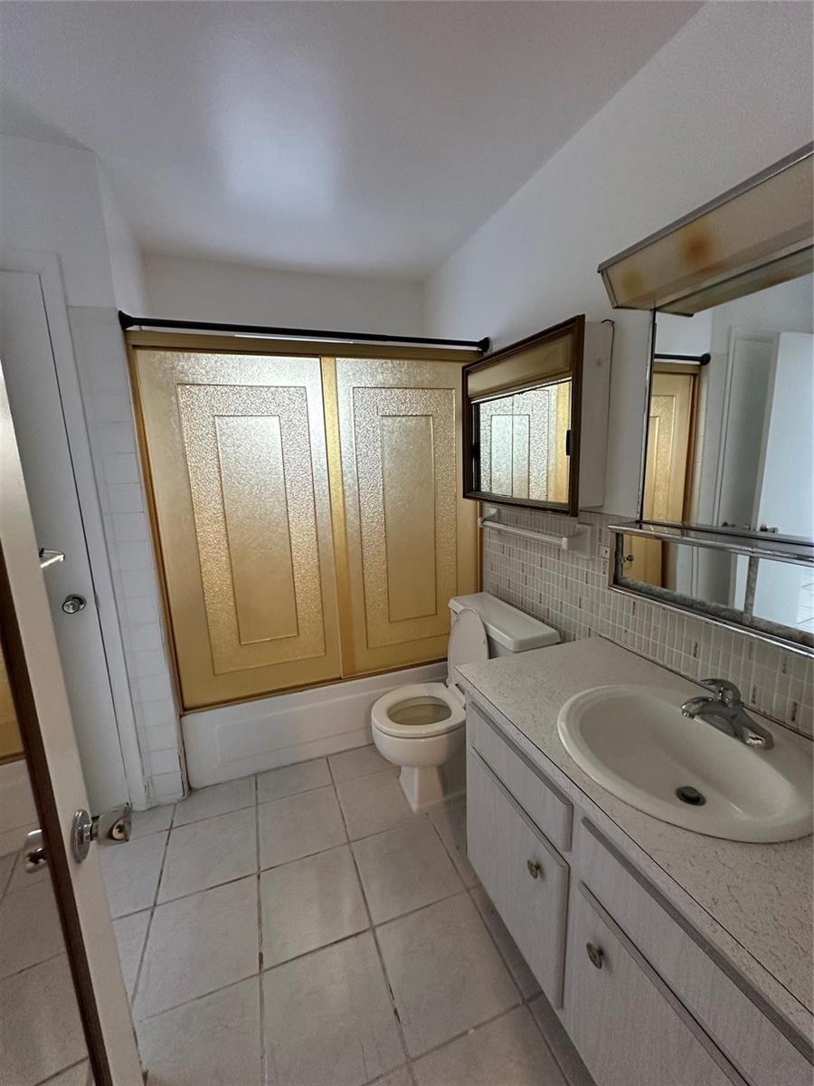 A bathroom features a white vanity, a toilet, and a shower with gold-framed sliding doors — 348 S Federal Highway # 2, Dania Beach FL 33004, DANIA BEACH, FL