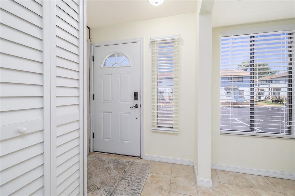 An entryway features a white front door, tiled flooring, a closet, and windows with blinds — 3333 S RIDGEWOOD AVENUE UNIT 27G, PORT ORANGE, FL