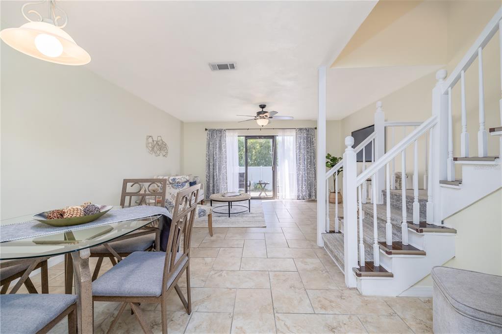 A dining area and living room with tile floors, a staircase, and sliding glass doors — 3333 S RIDGEWOOD AVENUE UNIT 27G, PORT ORANGE, FL