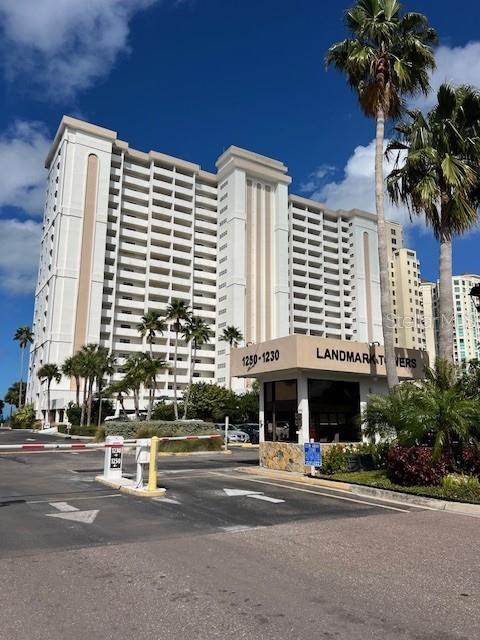 A tall, multi-story residential building stands behind a gated entrance with a security booth — 1230 GULF BOULEVARD UNIT 1507, CLEARWATER, FL