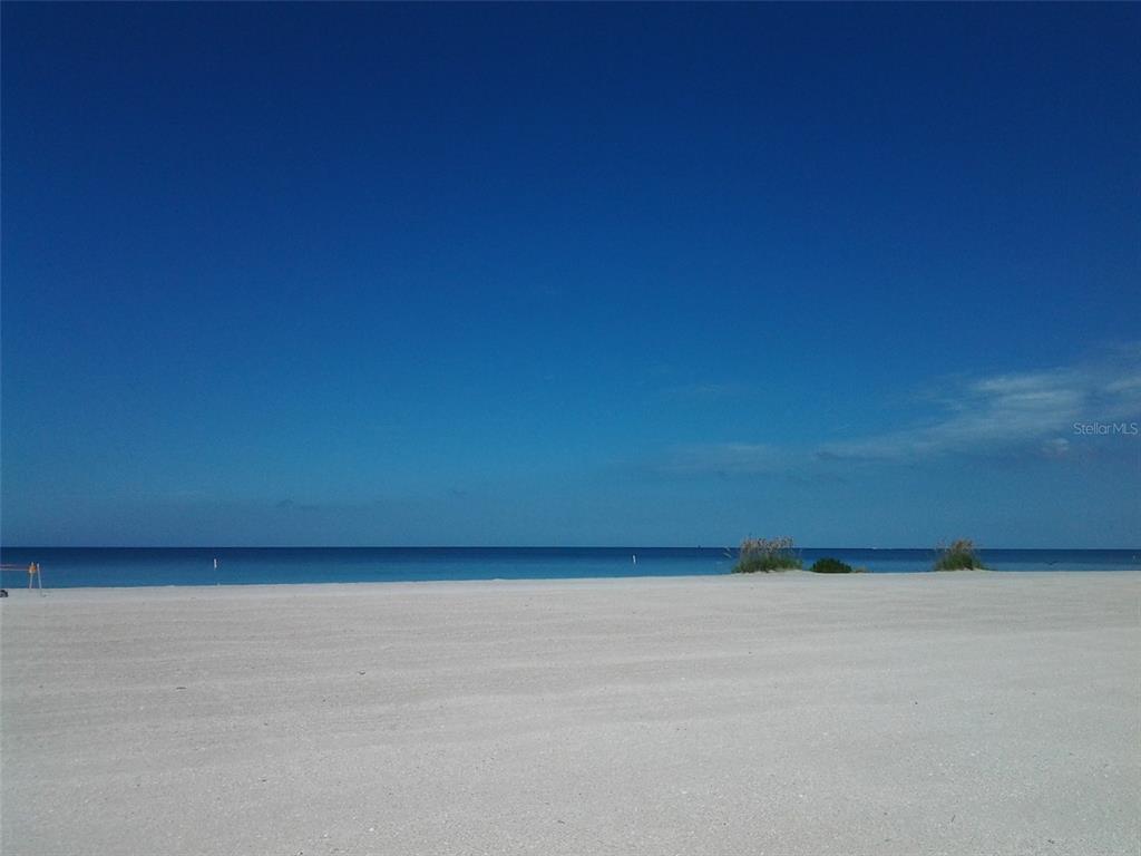 A wide, sandy beach meets the calm blue ocean under a clear sky — 1230 GULF BOULEVARD UNIT 1507, CLEARWATER, FL