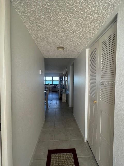 A hallway with tile flooring leads toward a living area with a view of the ocean — 1230 GULF BOULEVARD UNIT 1507, CLEARWATER, FL