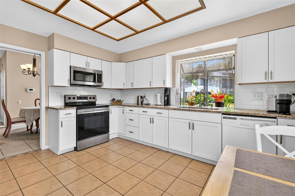 A kitchen with white cabinets, stainless steel appliances, granite countertops, and light-colored tile flooring — 1846 LAKE CYPRESS DRIVE UNIT 1846, SAFETY HARBOR, FL