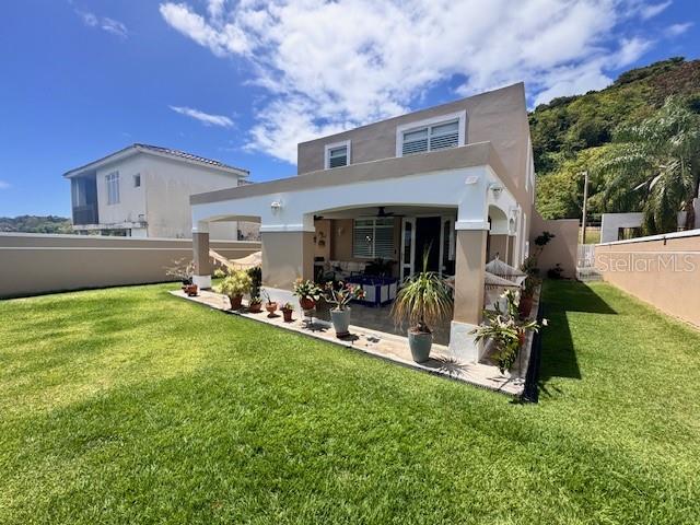 A two-story house with a covered patio and potted plants sits on a grassy lawn — Camino del Miradero 09, HUMACAO, PR