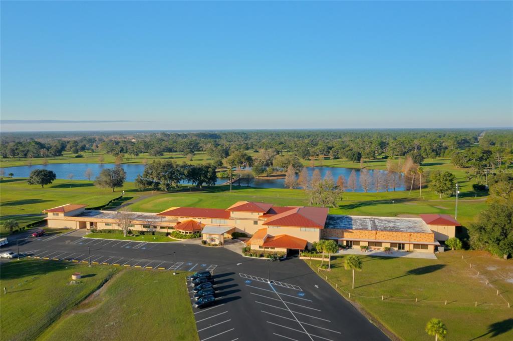 An aerial view shows a large clubhouse building with a red roof and parking lot — 1005 AZALEA DRIVE, INDIAN LAKE ESTATES, FL