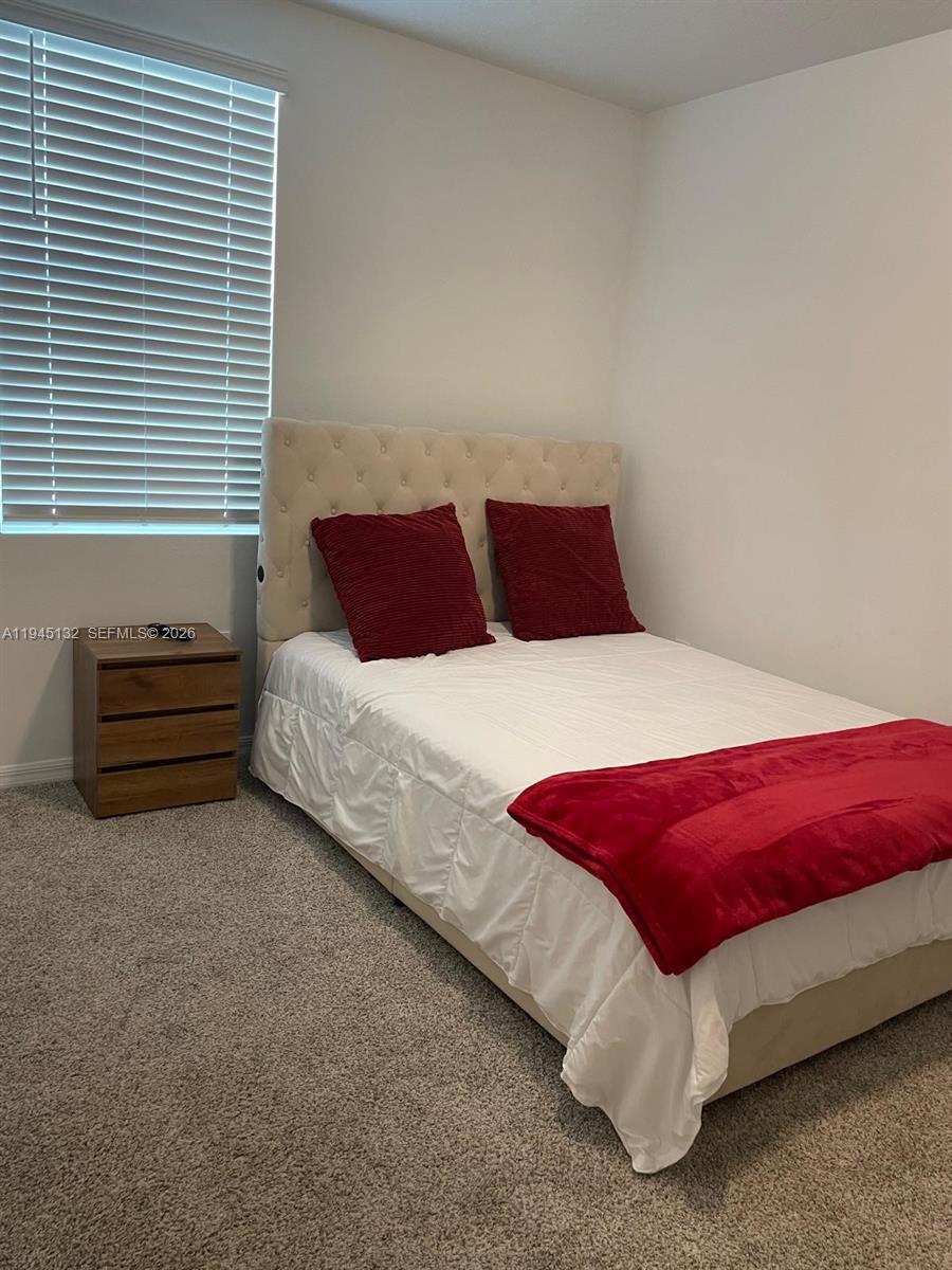 A bedroom features a tufted beige headboard, a white bedspread, red pillows, and a nightstand — 3829 GIORGIO, Winter Haven FL 33884, WINTER HAVEN, FL