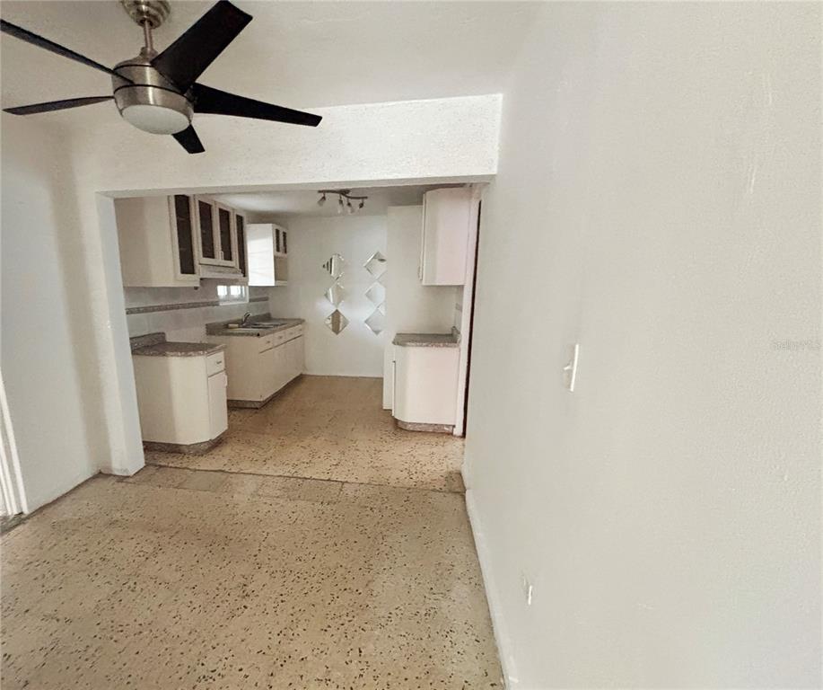 An empty room with light-colored walls, terrazzo flooring, and windows with metal security bars — Daniel Bonilla 30 BUENA VISTA, CAYEY, PR