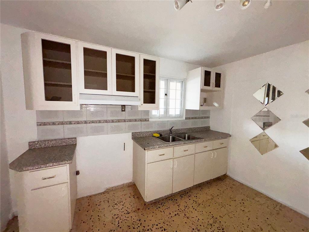 A kitchen with white cabinets, speckled countertops, and diamond-shaped wall mirrors — Daniel Bonilla 30 BUENA VISTA, CAYEY, PR