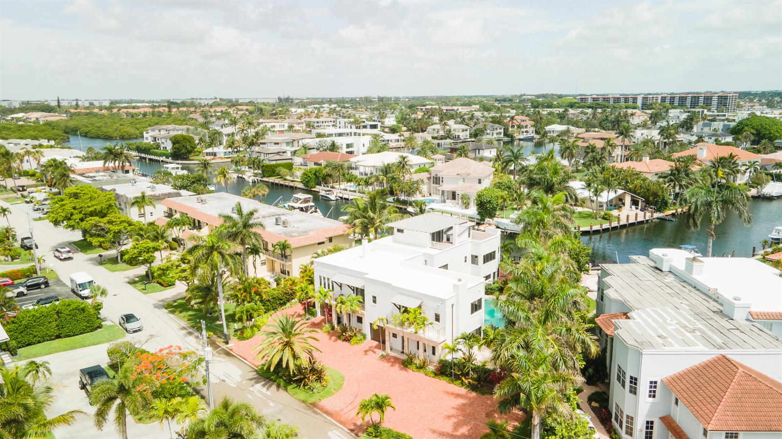 An aerial view shows a white multi-story house with a red driveway near a canal — 1121 Bel Air Drive, Highland Beach FL 33487, HIGHLAND BEACH, FL