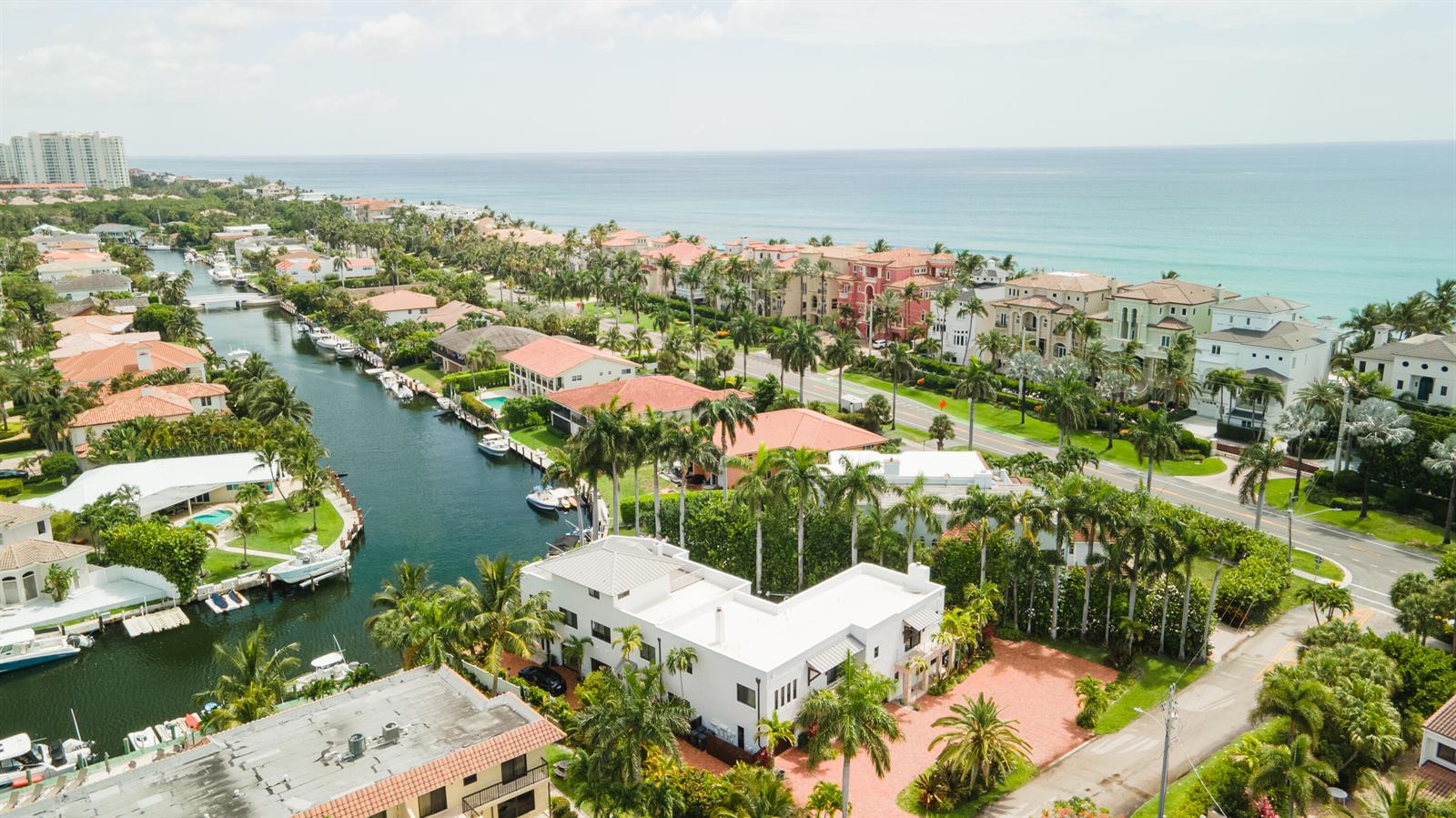 An aerial view shows waterfront homes along a canal leading to the ocean — 1121 Bel Air Drive, Highland Beach FL 33487, HIGHLAND BEACH, FL