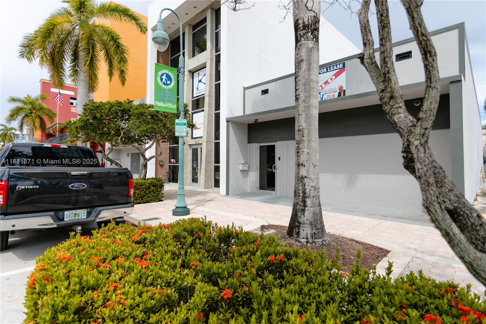 A black pickup truck is parked in front of a modern commercial building with palm trees — 1911 Harrison St # 5, Hollywood FL 33020, HOLLYWOOD, FL