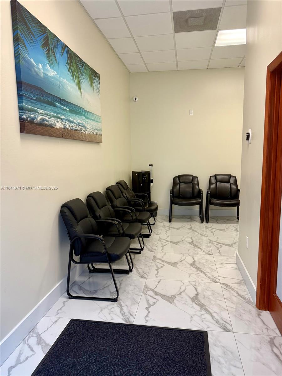 This waiting room features black chairs, white marble-patterned tile flooring, and a beach-themed wall art piece — 1911 Harrison St # 5, Hollywood FL 33020, HOLLYWOOD, FL