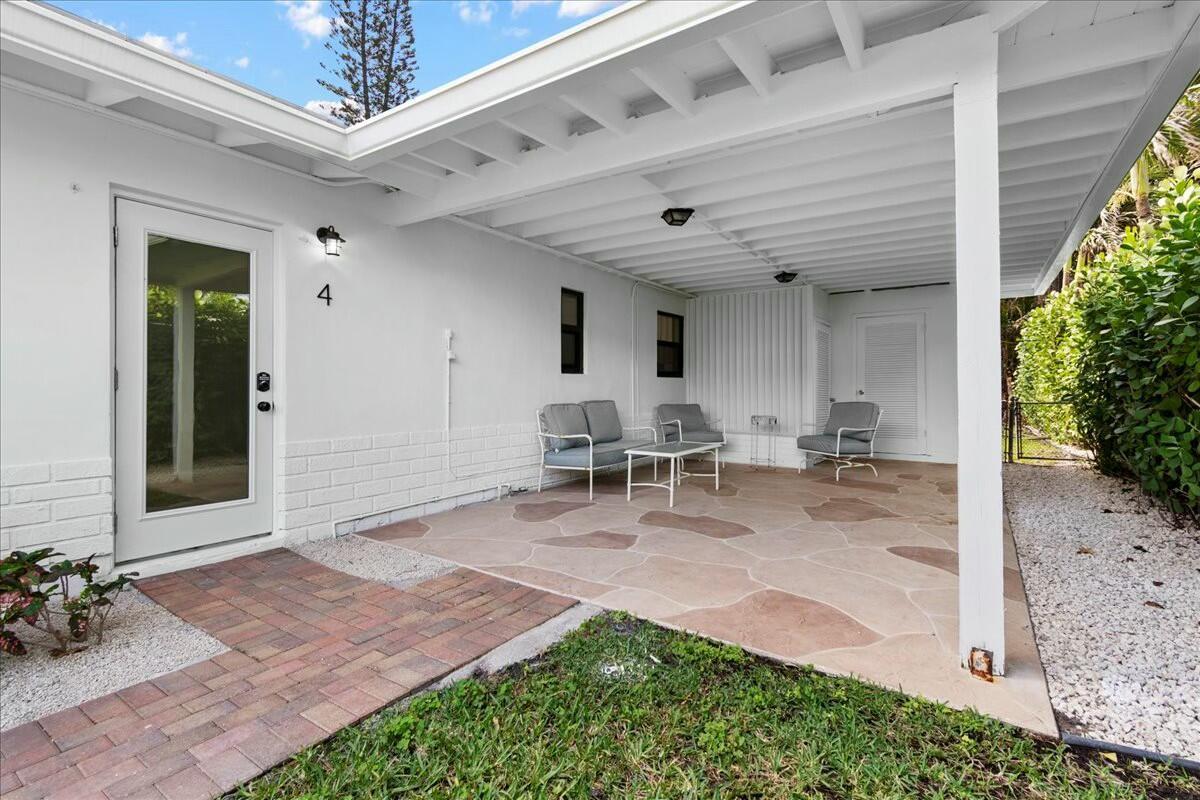 A covered patio features a stone-patterned floor, white walls, and outdoor seating furniture — 18 Adams Road, Ocean Ridge FL 33435, OCEAN RIDGE, FL