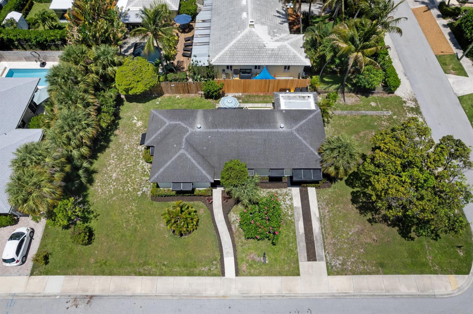 An aerial view shows a single-story house with a dark roof, driveway, and landscaped yard — 1725 N Lakeside Drive, FL 33460, FL