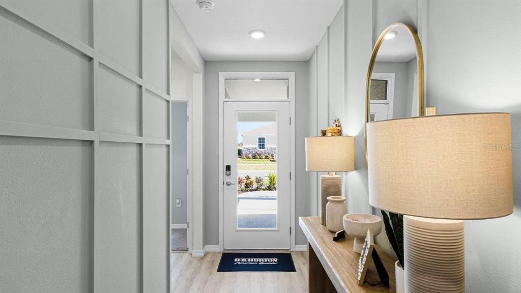 A bright entryway features light gray walls, board and batten trim, and a glass-paneled door — 7881 FORREST FOX WAY, LAKELAND, FL