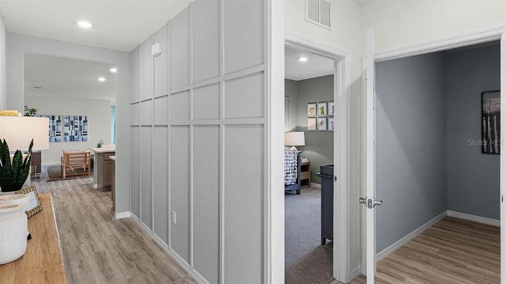 A hallway with board and batten wall paneling leads to a living area and bedrooms — 7881 FORREST FOX WAY, LAKELAND, FL