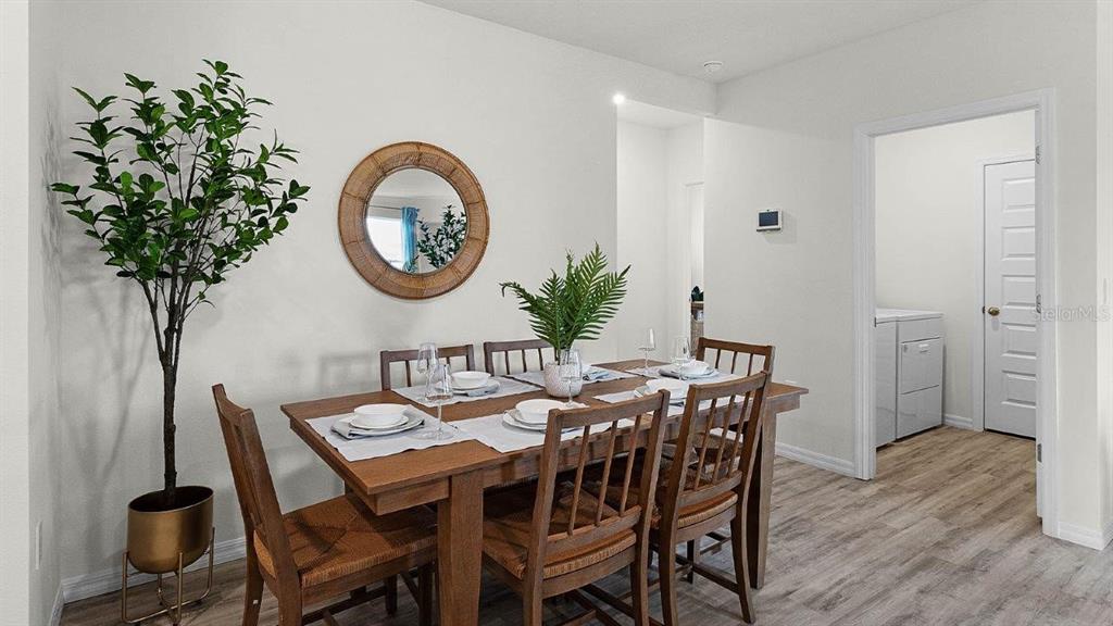A dining room features a wooden table with chairs, a round mirror, and a potted plant — 7881 FORREST FOX WAY, LAKELAND, FL