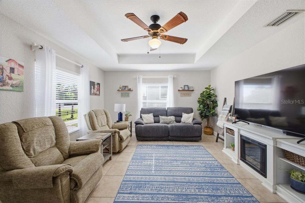 A living room features a tray ceiling, a ceiling fan, a fireplace, and tiled floors — 2441 17TH STREET W, PALMETTO, FL