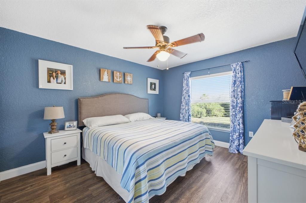 A bedroom features blue walls, a bed with a striped quilt, and wood-look flooring — 2441 17TH STREET W, PALMETTO, FL