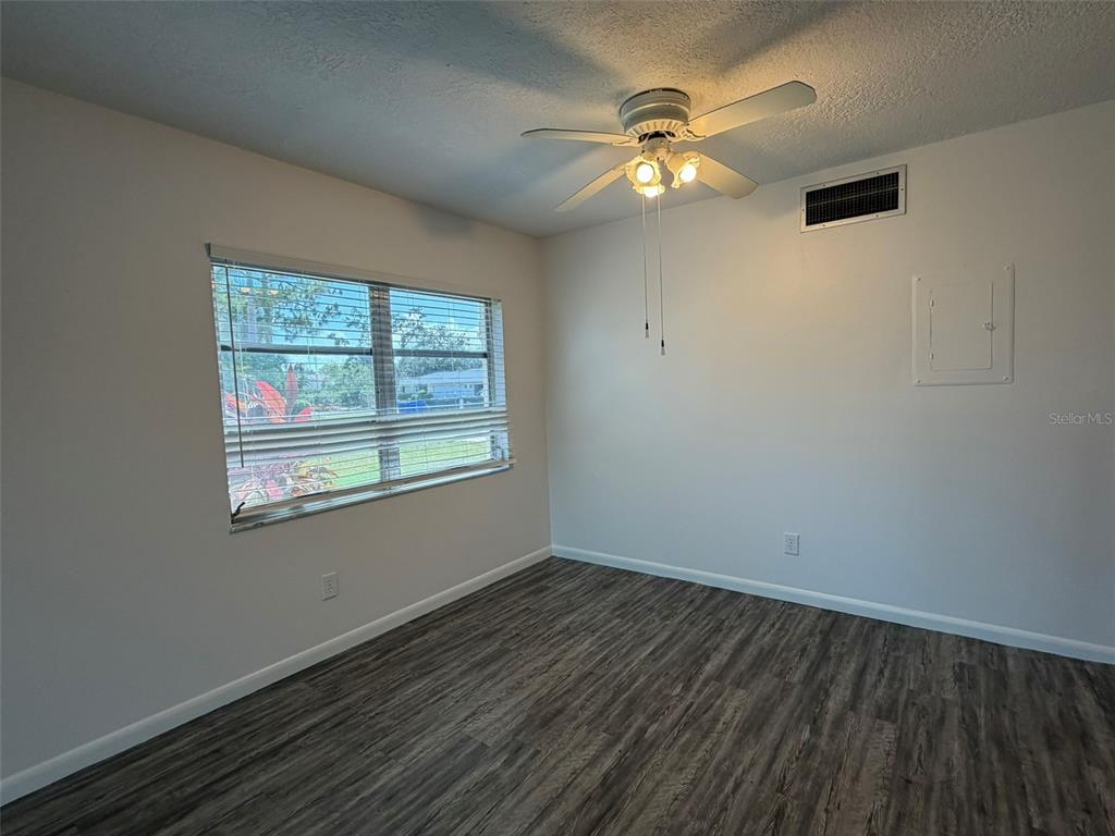 An empty bedroom features light gray walls, dark wood-look flooring, and a ceiling fan — 7153 W COUNTRY CLUB DR N UNIT 145, SARASOTA, FL