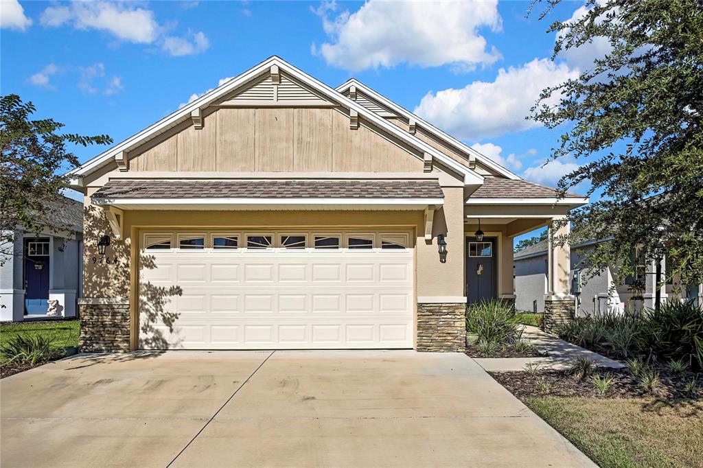 A single-story house with a beige stucco exterior, stone accents, and a two-car garage — 9764 SW 100TH AVENUE ROAD, OCALA, FL