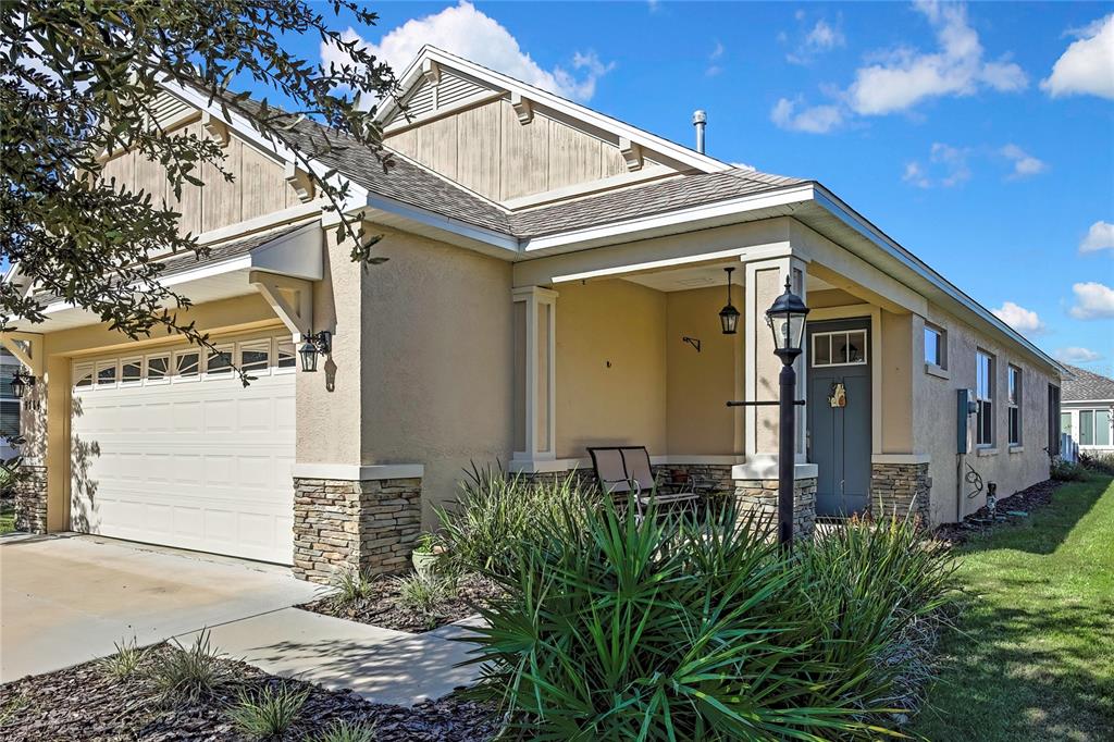 A single-story house exterior features a two-car garage, a covered porch, and stone accents — 9764 SW 100TH AVENUE ROAD, OCALA, FL