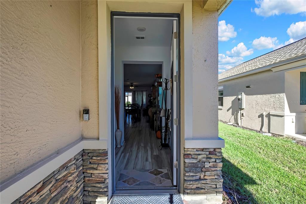 A view through an open front door showing an interior hallway with wood-look flooring — 9764 SW 100TH AVENUE ROAD, OCALA, FL