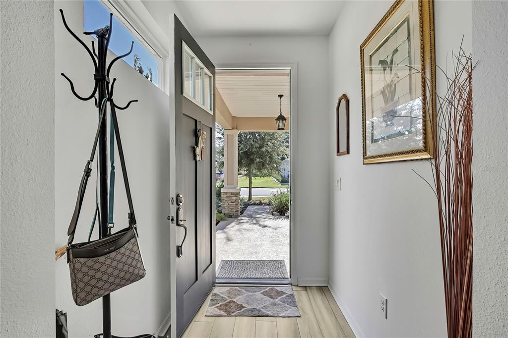 An entryway features a coat rack, a dark front door, and a view of the porch — 9764 SW 100TH AVENUE ROAD, OCALA, FL