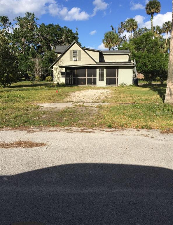 A two-story house with a screened-in porch sits behind a gravel driveway and lawn — 226 WILDWOOD AVENUE, EDGEWATER, FL