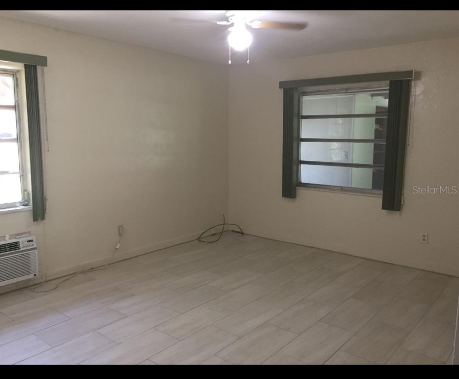 An empty room with light-colored tile flooring, a ceiling fan, and two windows — 226 WILDWOOD AVENUE, EDGEWATER, FL
