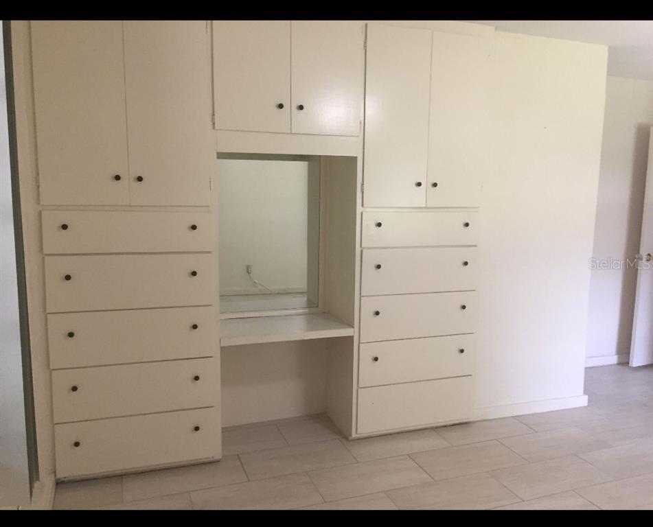 A bedroom wall features a built-in white vanity unit with surrounding cabinets and drawers — 226 WILDWOOD AVENUE, EDGEWATER, FL