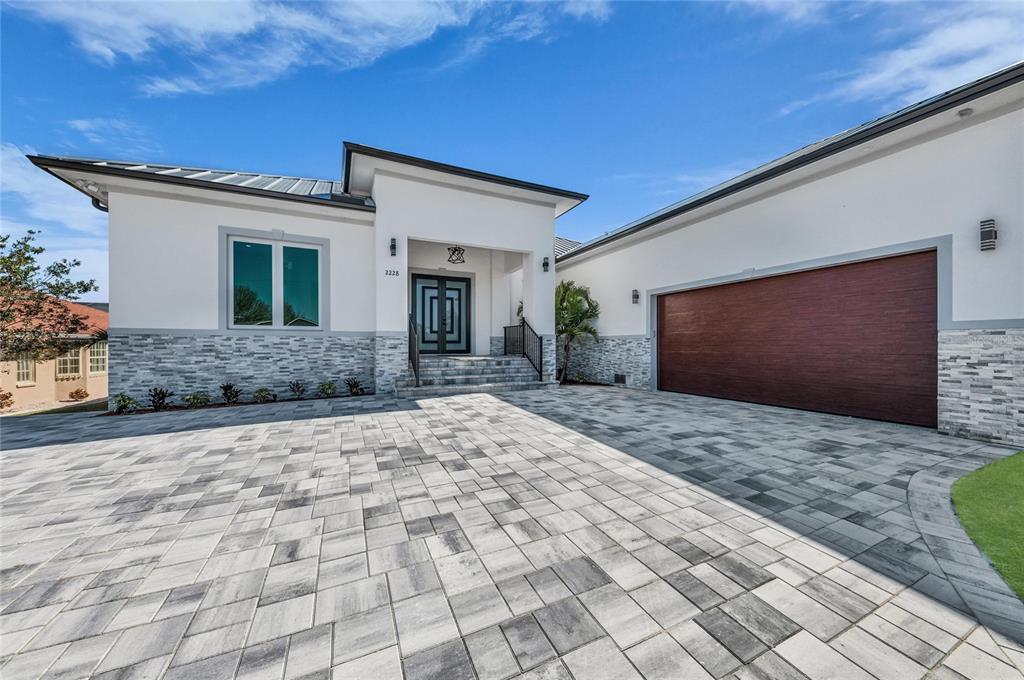 A modern single-story house with a metal roof, white stucco walls, and stone veneer base — 2228 HARBOUR DRIVE, PUNTA GORDA, FL