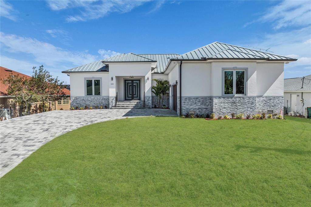 A modern house exterior features a stone facade, a wood-look garage door, and paver driveway — 2228 HARBOUR DRIVE, PUNTA GORDA, FL