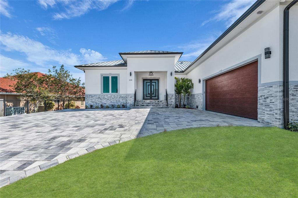 A modern single-story house features a paved driveway, stone accents, and a wooden garage door — 2228 HARBOUR DRIVE, PUNTA GORDA, FL