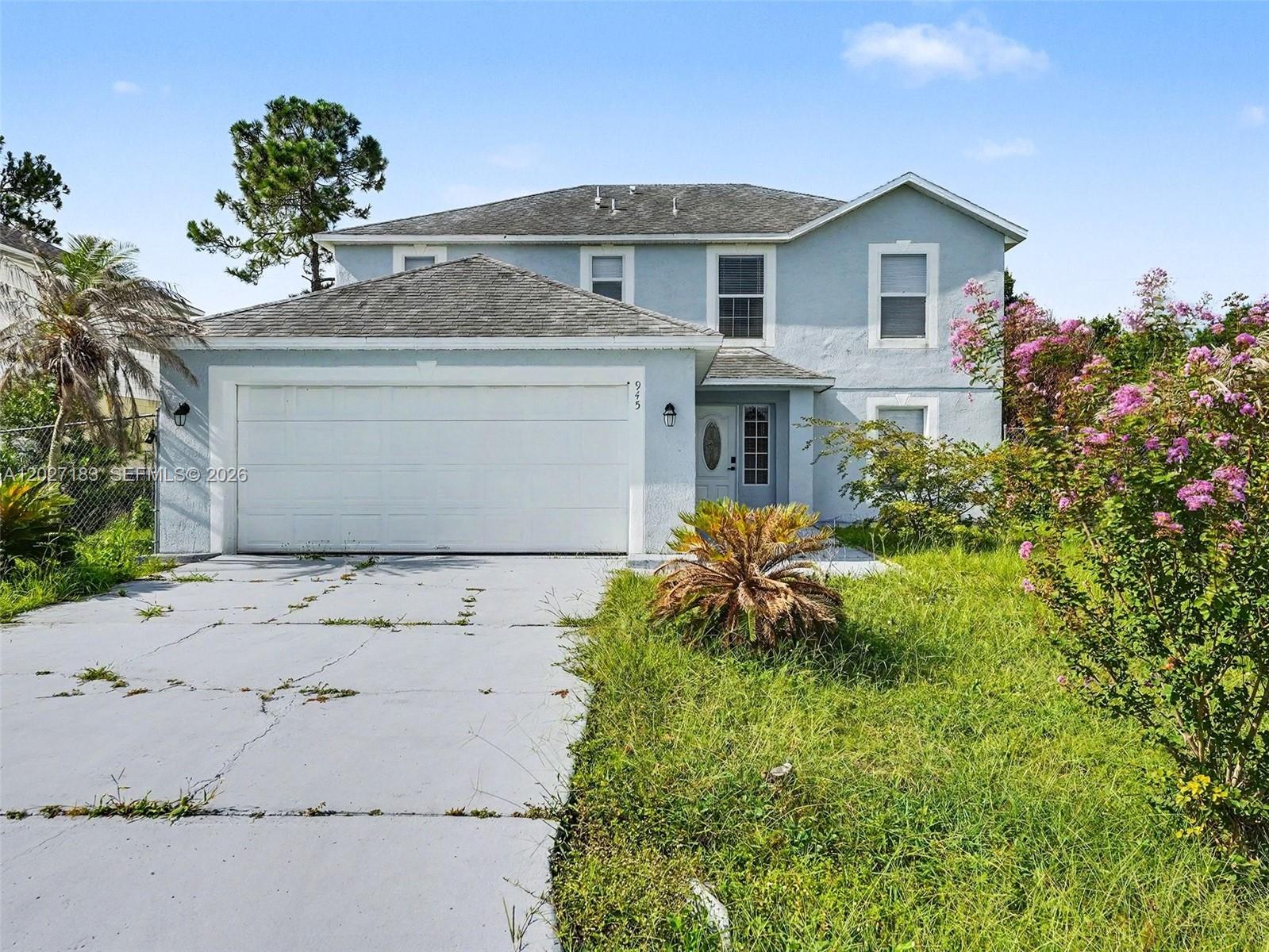 A two-story light blue house features a two-car garage and an overgrown front lawn — 945 Gateshead, Kissimmee FL 34758, KISSIMMEE, FL