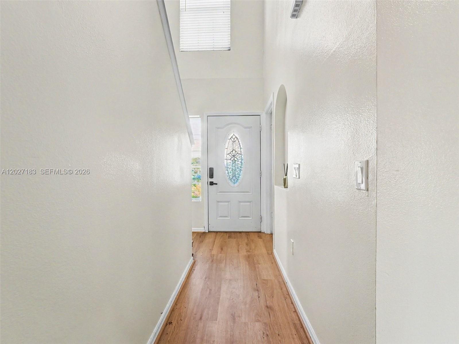 A narrow entryway features light wood-look flooring, white walls, and a front door with glass — 945 Gateshead, Kissimmee FL 34758, KISSIMMEE, FL
